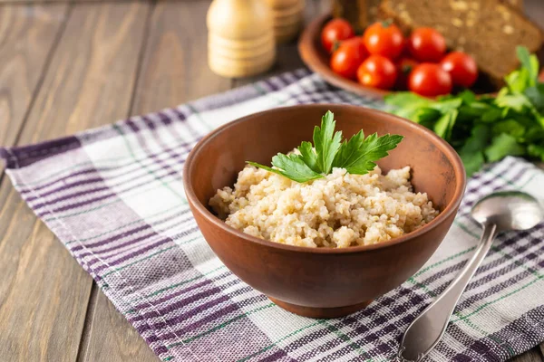 Colazione vegetariana sana con porridge di grano, pane, pomodori e prezzemolo su tavolo rustico in legno — Foto Stock