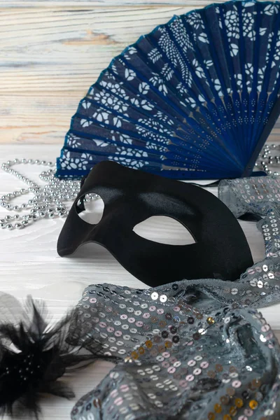 Festliche Karnevalsaccessoires, Maske, eleganter Fächer und Schmuck auf weißem Holzgrund. — Stockfoto