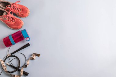 Kilo vermek isteyen sporcu ya da kadın konsepti, ip atlama, su için pembe parlak şişe ve beyaz tahta zeminde spor ayakkabılar. Metnin için kopyalama alanı