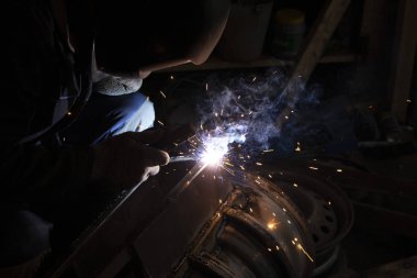 Kaynak yapan adam metal pişirir. Kaynak makinesinden çıkan kıvılcımlar.