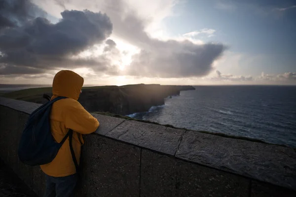 Homem com casaco amarelo olhando para o horizonte em falésias de Moher — Fotografia de Stock