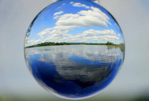 Красивое озеро, белые облака и голубое небо, захваченные через хрустальный шар — стоковое фото