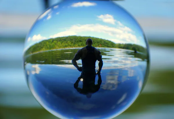Силуэт человека в воде на озере, захваченный хрустальным шаром — стоковое фото