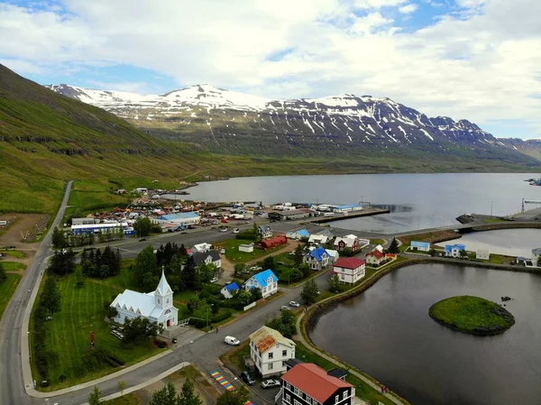 Seydisfjordur, Islândia - 23 de junho de 2019 - A vista aérea dos edifícios, casas residenciais, estradas e montanhas nevadas da cidade no verão — Fotografia de Stock