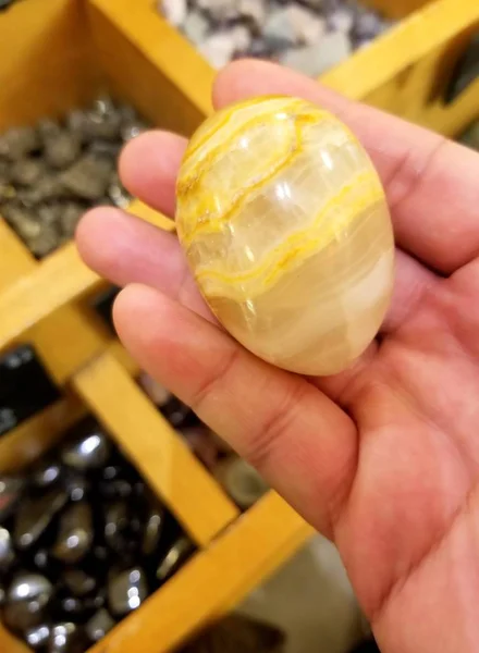 Segurando uma forma de ovo Onyx pedra na cor amarelo claro — Fotografia de Stock