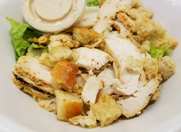 Beyaz bir kasede ızgara tavuk sezar salatası.