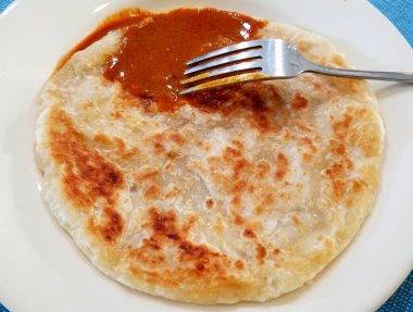 Köri soslu ve gümüş çatallı Roti Canai adında Malezya usulü kızarmış krep.