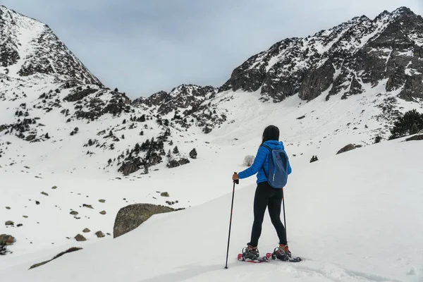 높은 산에서 눈 라켓을 든 채걷고 있는 젊은 여자 — 스톡 사진