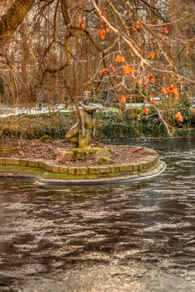 Lagoa congelada com estátua e belas árvores — Fotografia de Stock