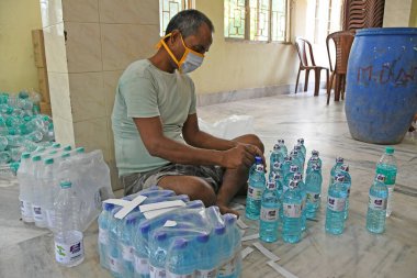 Burdwan, Purba Bardhaman Bölgesi, Batı Bengal / Hindistan - 19.04.2020: Burdwan merkezli kuruluş 'Palla Yolu Pallimongal Samity' Kamu Özel Ortaklığı projesinde alkol bazlı el dezenfektanları üretiyor.