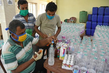Burdwan, Purba Bardhaman Bölgesi, Batı Bengal / Hindistan - 19.04.2020: Burdwan merkezli kuruluş 'Palla Yolu Pallimongal Samity' Kamu Özel Ortaklığı projesinde alkol bazlı el dezenfektanları üretiyor.