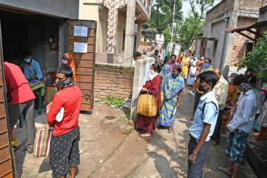 Burdwan Town, Purba Bardhaman Bölgesi, Batı Bengal / Hindistan - 02.05.2020: Novel Coronavirus (COVID-19) salgını nedeniyle kilitlenme döneminde Burdwan kasabasındaki bir karne dükkanında gıda tahılları toplamak için kuyrukta bekleyenler.
