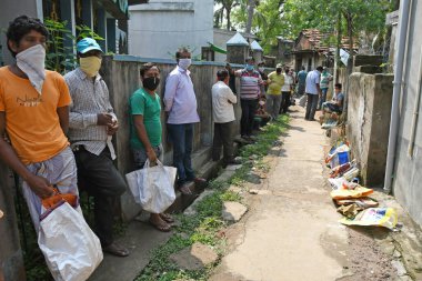 Burdwan Town, Purba Bardhaman Bölgesi, Batı Bengal / Hindistan - 02.05.2020: Novel Coronavirus (COVID-19) salgını nedeniyle kilitlenme döneminde Burdwan kasabasındaki bir karne dükkanında gıda tahılları toplamak için kuyrukta bekleyenler.