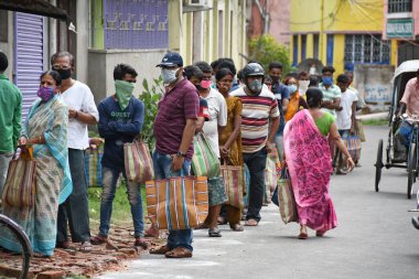Burdwan Town, Purba Bardhaman Bölgesi, Batı Bengal / Hindistan - 02.05.2020: Novel Coronavirus (COVID-19) salgını nedeniyle kilitlenme döneminde Burdwan kasabasındaki bir karne dükkanında gıda tahılları toplamak için kuyrukta bekleyenler.