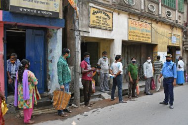 Burdwan Town, Purba Bardhaman Bölgesi, Batı Bengal / Hindistan - 02.05.2020: Novel Coronavirus (COVID-19) salgını nedeniyle kilitlenme döneminde Burdwan kasabasındaki bir karne dükkanında gıda tahılları toplamak için kuyrukta bekleyenler.