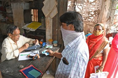 Burdwan Town, Purba Bardhaman Bölgesi, Batı Bengal / Hindistan - 02.05.2020: Novel Coronavirus (COVID-19) salgını nedeniyle kilitlenme döneminde Burdwan kasabasındaki bir karne dükkanında gıda tahılları toplamak için kuyrukta bekleyenler.