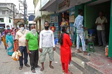 Burdwan Town, Purba Bardhaman Bölgesi, Batı Bengal / Hindistan - 02.05.2020: Novel Coronavirus (COVID-19) salgını nedeniyle kilitlenme döneminde Burdwan kasabasındaki bir karne dükkanında gıda tahılları toplamak için kuyrukta bekleyenler.