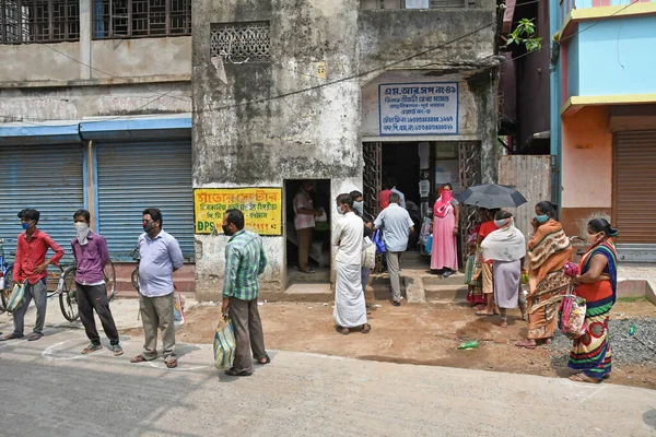 Burdwan Town, Purba Bardhaman Bölgesi, Batı Bengal / Hindistan - 02.05.2020: Novel Coronavirus (COVID-19) salgını nedeniyle kilitlenme döneminde Burdwan kasabasındaki bir karne dükkanında gıda tahılları toplamak için kuyrukta bekleyenler.