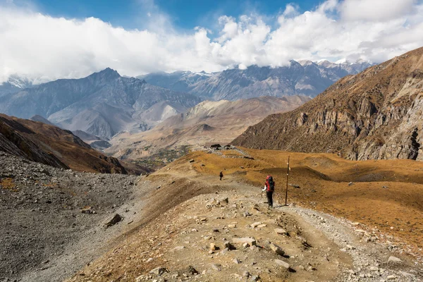 Trekker discesa montagna su sentiero sterrato circondato da terre desolate . — Foto Stock