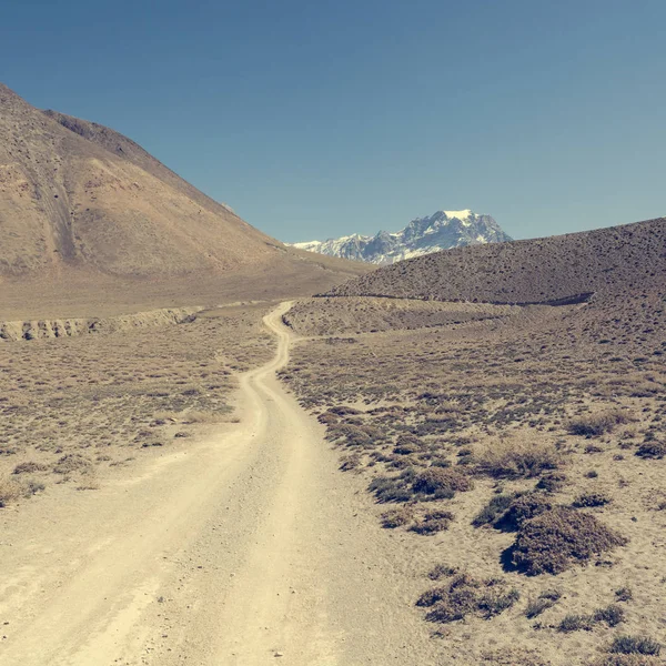 Strada sterrata attraverso aride terre desolate di montagna . — Foto Stock