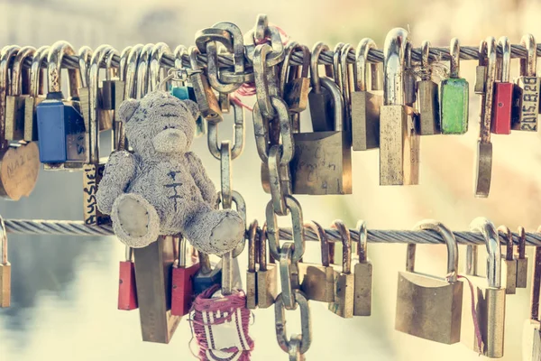 Teddy bear with love locks on a metal bridge. — Stock Photo, Image