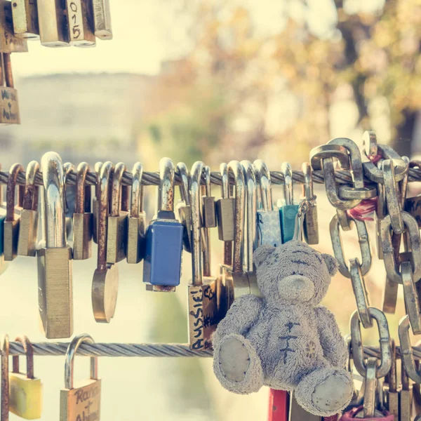 Teddy bear with love locks on a metal bridge. — Stock Photo, Image