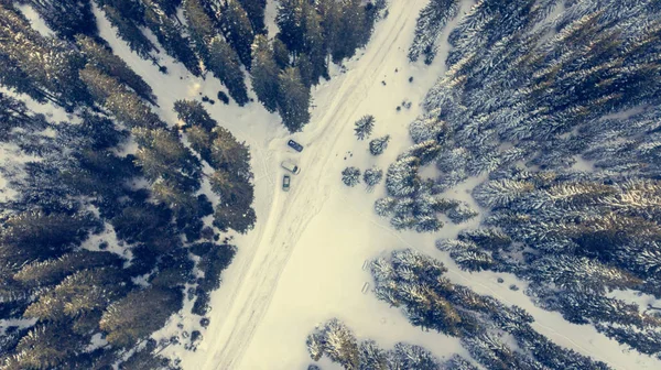 Vista aérea da estrada coberta de neve através de uma floresta . — Fotografia de Stock