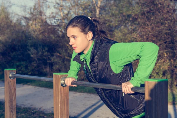 Attractive brunette doing pushups in park. — Stock Photo, Image