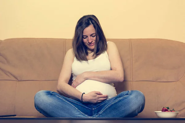 Intimes Porträt einer jungen Schwangeren, die ihren Bauch hält. — Stockfoto