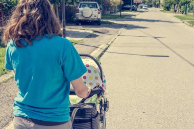 Rahat giyinmiş anne itme bir bebek arabası.