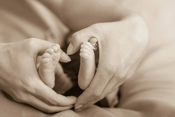 Mothers hands forming a hearth around baby feet. — Stock Photo, Image