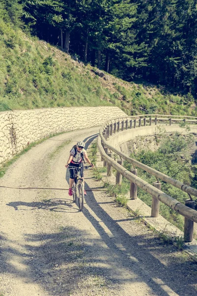 Attractive female cyclist tackling a steep road. — Stock Photo, Image