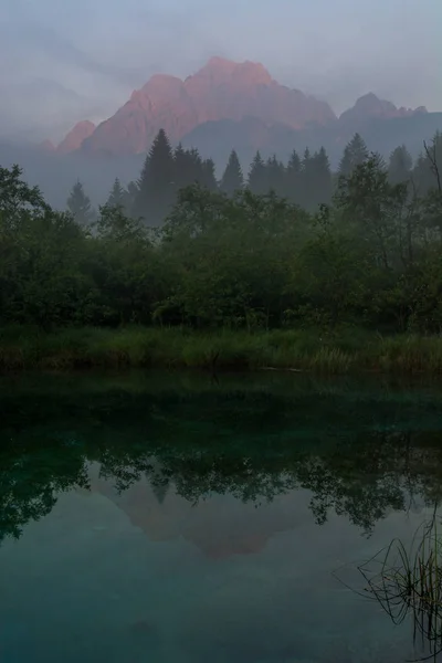 Morning mists rising above lake surrounded by mountains. — Stock Photo, Image