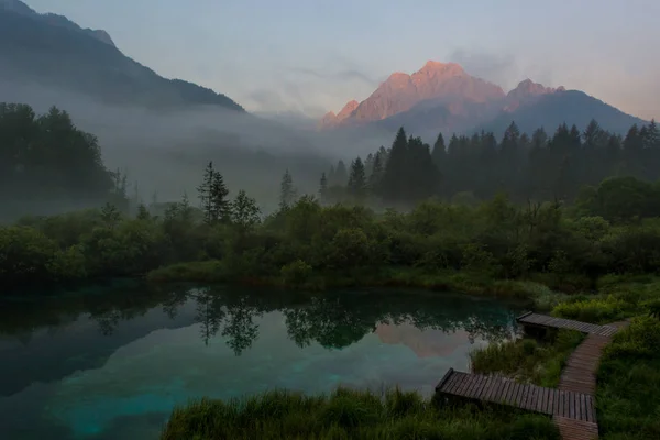Morgonens dimmor stiger ovanför sjön omgiven av berg. — Stockfoto