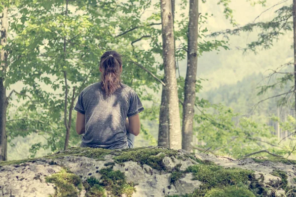 Jonge vrouw mediteren op bos rots. — Stockfoto