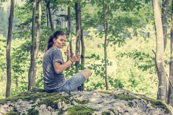 Young woman looking across her shoulder on a forest rock. — Stock Photo, Image