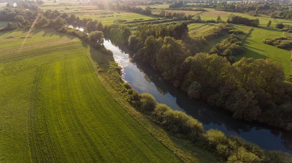 Vista aérea del río doblándose a través de los campos al atardecer . —  Fotos de Stock