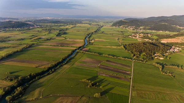 Luchtfoto van rivier buigen over de velden bij zonsondergang. — Stockfoto