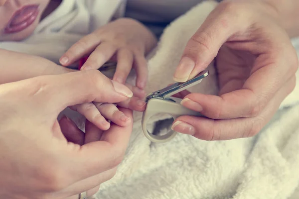 Matka, delikatnie cięcia jej paznokcie dziecka. — Zdjęcie stockowe