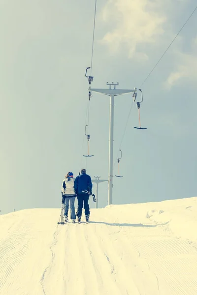 Couple riding a button ski lift.