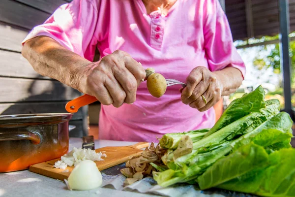 Closeup of elderly hands peaing potatoe. — Stock Photo, Image