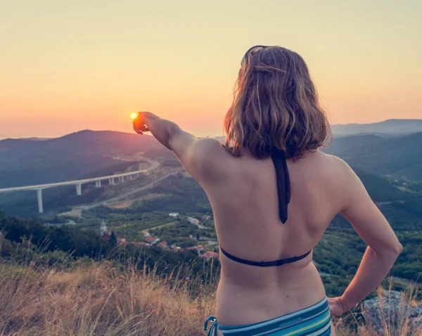 Attraktive Brünette zeigt auf die untergehende Sonne. — Stockfoto