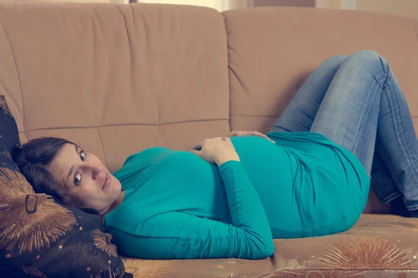 Беременная женщина отдыхает на диване . — стоковое фото