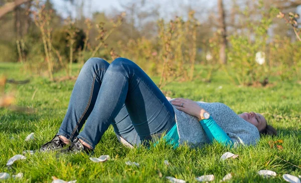 Expecting mother lying on grass in public park. — Stock Photo, Image