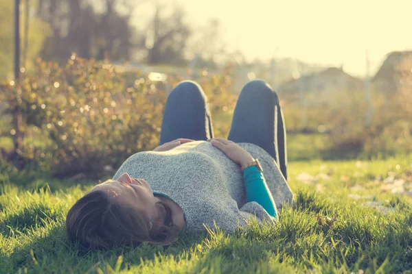 Expecting mother lying on grass in public park. — Stock Photo, Image