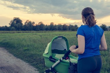 Etkin anne günbatımında bir bebek arabası itme.