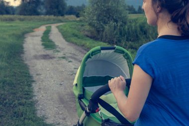 Etkin anne günbatımında bir bebek arabası itme.