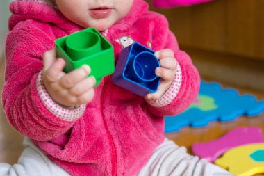 Ahşap zemin üzerinde renkli tuğla ile oynayan bebek.