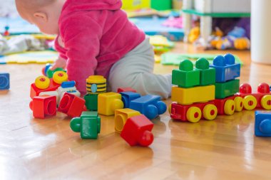 Ahşap zemin üzerinde renkli tuğla ile oynayan bebek.