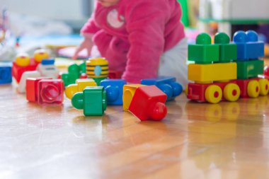 Ahşap zemin üzerinde renkli tuğla ile oynayan bebek.